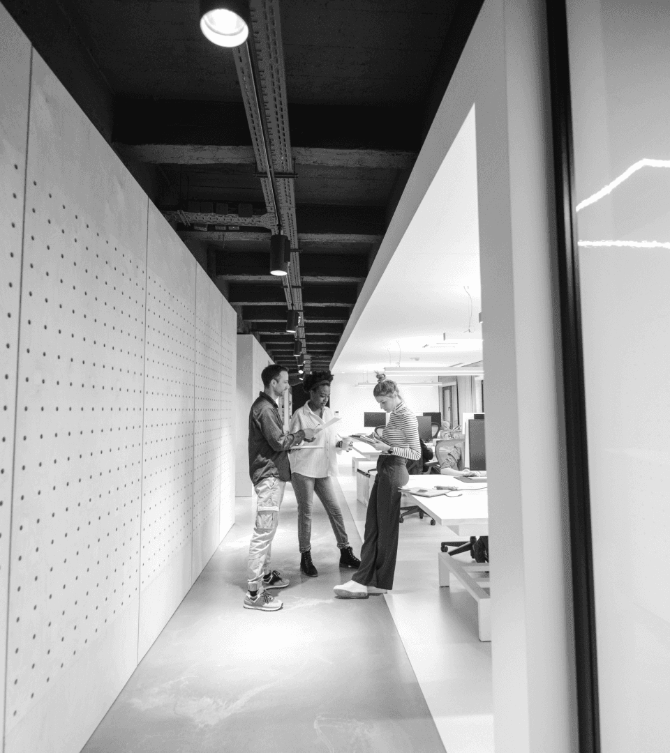 Three co-workers chat in hallway.