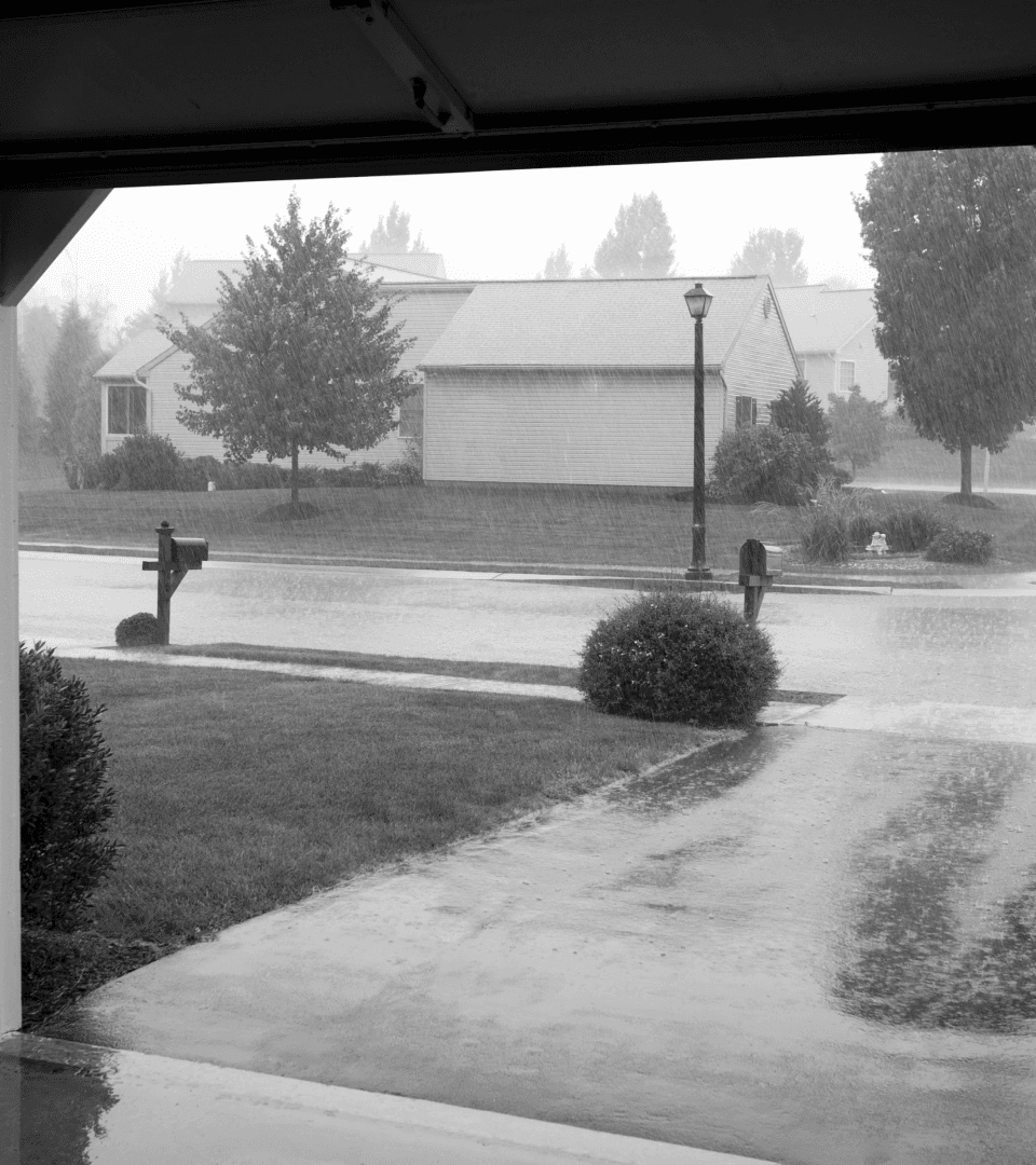 Looking out of garage into a heavy rainstorm on the street.