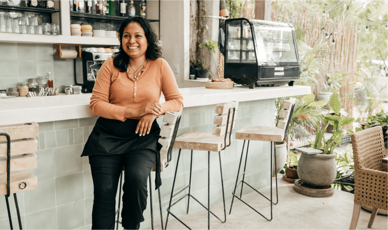 A smiling woman at the counter of a coffee shop.