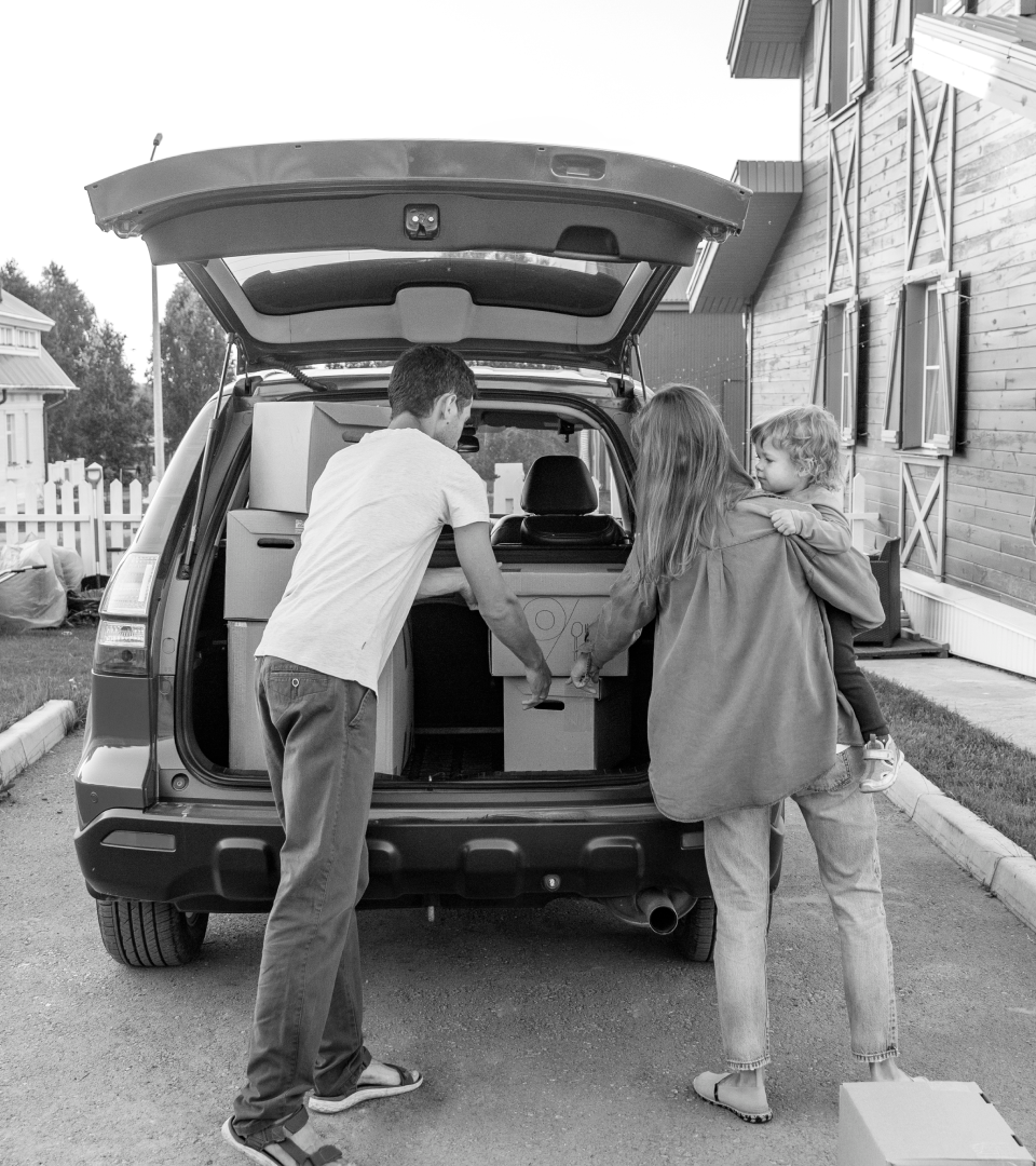 A family packs boxes into the back of their car.