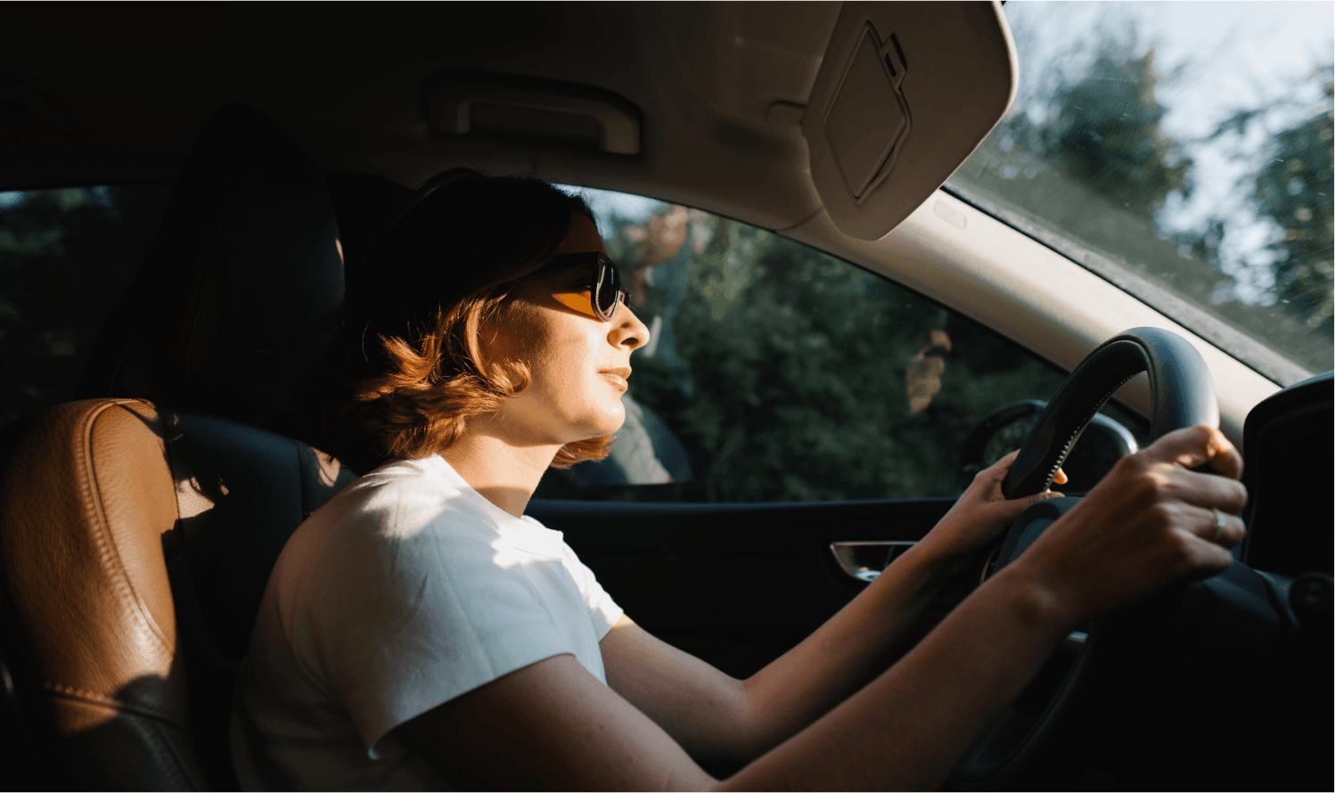 A woman in sunglasses drives her car.