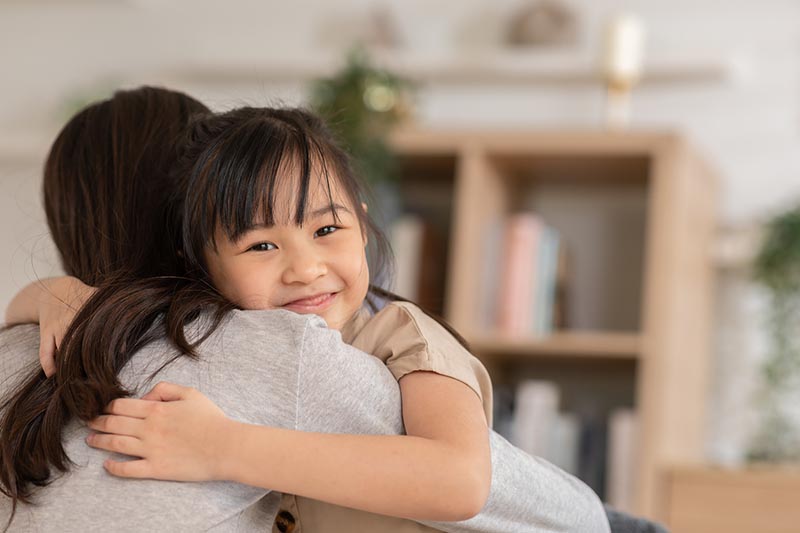 A mom hugging her daughter and considering life insurance.