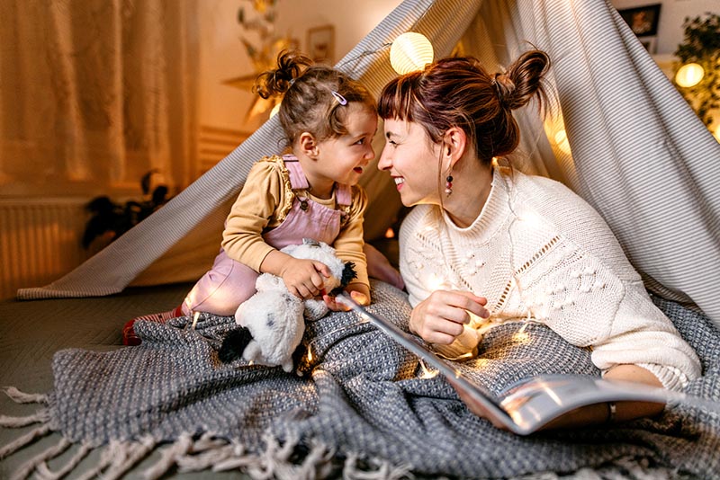 A mom and daughter play together in a play tent