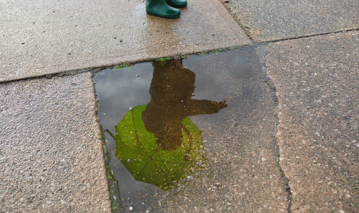 A child's reflection in a puddle.