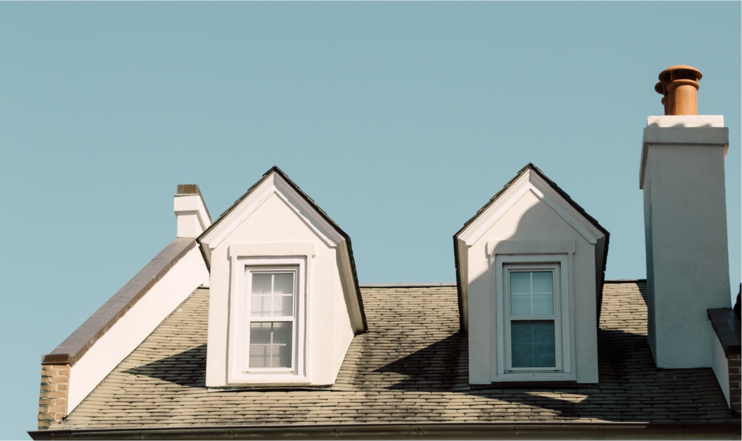 Roof of house with two dormer windows and a chimney.